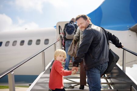 Little boy and his father climb the gangway into the plane against the background of people. Back view. Travel for family with little kids.の写真素材