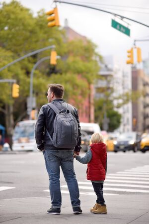Little boy with his father looks on signal of traffic light on crossroads of New York City, USA. Traffic Laws. Safety in the big city.の写真素材