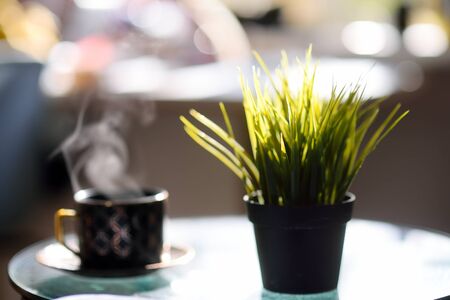 Sunny morning at home. Cup of hot freshly brewed coffee on the table in kitchen. Cozy interior....