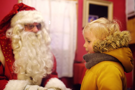 Tallinn, Estonia - 6 January 2019: Little boy talking with Santa Claus on Christmas fair. Child dreams of a gift that he can receive. Magic mail of Santa Claus.のeditorial素材