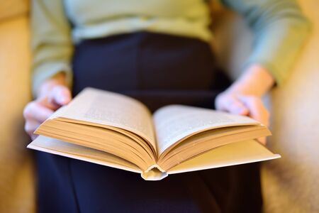 Eldrely woman is reading a book on couch at home. Senior lady lifestyles. Active longevity concepts.