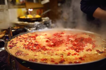 Hot food on Tallinn Christmas fair. Stewed cabbage with berry in frying pan. Steet food.の写真素材