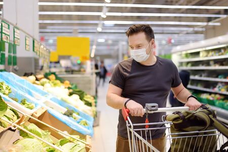 Man wearing disposable medical mask shopping in supermarket during virus pneumonia outbreak....