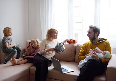 Difficulties of family with three kids during quarantine. Stay at home concept. Online working and household at the same time while quarantine. Bored parents with children.の写真素材