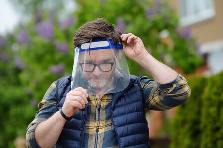 Man putting on face shield on street of city or public park. Safety during COVID-19 outbreak....