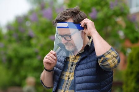 Man putting on face shield on street of city or public park. Safety during COVID-19 outbreak....
