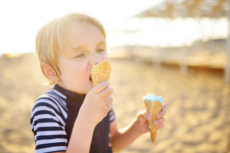 Preschooler boy eating ice cream on hot summer day on beach during family holiday.Gelato is loved delicacy for kids. Sweets are unhealthy food for children. Diabetes, obesity - diseases of metabolismの写真素材