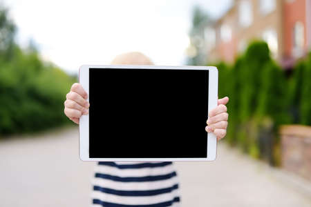 Little child holding with hands tablet pc with black screen for copy space and free text. Space for your advertising or information. Empty device screen.の写真素材