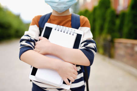 Child wearing face mask going at reopen school after covid-19 quarantine and lockdown. It is new normal for protection and prevention while outbreak of coronavirus or flu. Kids back to school concept.の写真素材