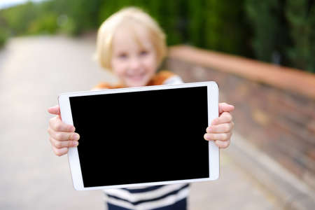Little child holding with hands tablet pc with black screen for copy space and free text. Space for your advertising or information. Empty device screen.の写真素材