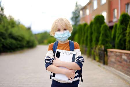 Child wearing face mask going at reopen school after covid-19 quarantine and lockdown. It is new normal for protection and prevention while outbreak of coronavirus or flu. Kids back to school concept.の写真素材