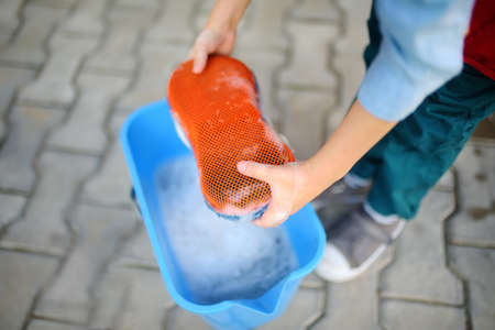 Preschooler boy helping his father washing family car. Little dad helper. Family with children spends time together in the backyardの写真素材