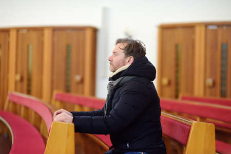 Religious middle age man praying and meditating in catholic church. Person begging for forgiveness...