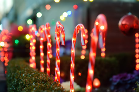 Close-up photo of Christmas and New Year decorations. Fence decorated with a garland like candy stick cane. Stylish outdoor Xmas decorationsの写真素材