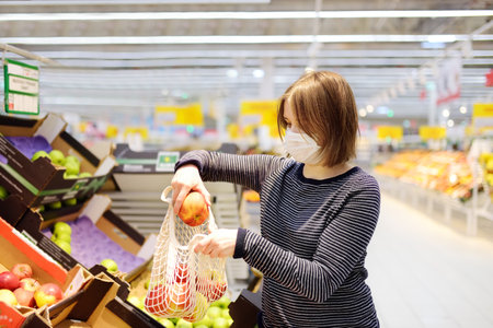 Young woman wearing protective medical face mask shopping in supermarketの写真素材