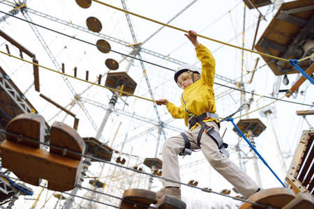 Little boy having fun in Adventure Park for children amoung ropes, stairs, bridges. Outdoor climbing adventure playground in public park. Activity entertainment for family with kidsの写真素材