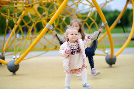 Two child having fun on outdoor playground. Spring / summer / autumn active sport leisure for kids. Outdoor activity for baby and preschooler. Equipment for children playground and park of entertainmentsの写真素材