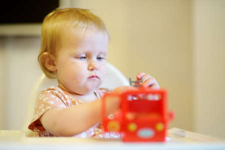 Cute baby girl playing with bright toy. Toddler having fun with eco educational toys. Game and entertainment for little kids at home. Early development for children. ? hild's lag in developmentの写真素材