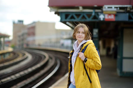 Beautiful young woman is waiting for a train on a platform in the New York subway. Transport of NYC,...