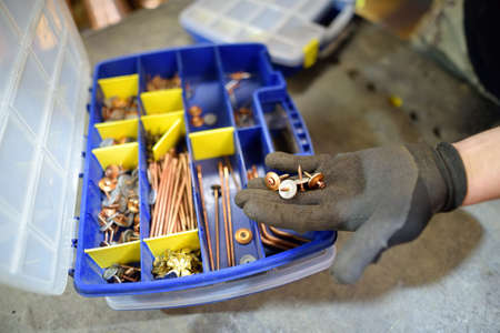 Worker choose a screws from the box, close-up of hand wearing in work glove. Do it yourself. Diy...