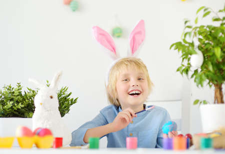 Cute boy paint eggs for Easter holiday. Preparing for the holiday is a joy for kids. Little child...