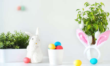 Colored eggs, cute little bunny and rabbit ears on the table on Easter day. Celebrating Easter at spring. painting eggs. Home decoration for holiday.の写真素材