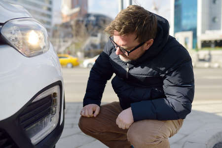 Man is watching a broken automobile headlight. Destroyed front light on the left side. car crash or accident. Insurance, repair. repair of auto.の写真素材