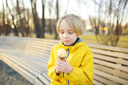 Little boy eating tasty ice cream cone outdoors during family stroll. Child have a snack on the go....