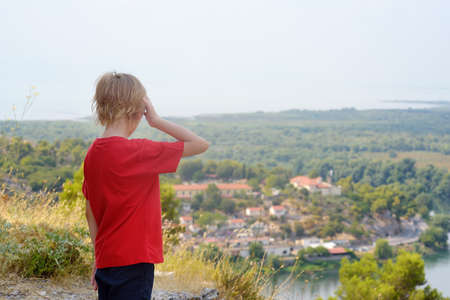 Little child tourist visiting famous fortress Rozafa near Shkodra city. Boy admiring view of valey river Buna, Skadar Lake and mountains. Travel and tourism in Balkanの写真素材