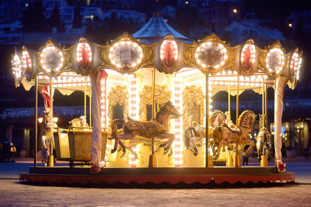 Budva, Montenegro - January 9, 2022: Vintage carousel (merry go round) near old town of Budva on Christmas fair. Outdoor entertainment activity for family with children on winter holidaysのeditorial素材