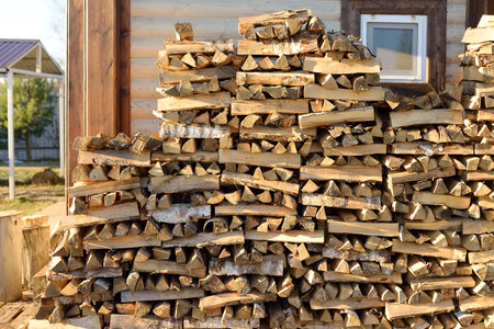 A large woodpile of firewood is stacked in the yard next to the village house. A supply of firewood...