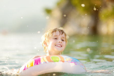 Little boy swimming with colorful floating ring in sea on sunny summer day. Cute child playing in...