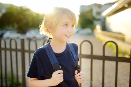 Portrait of cute smart preteen boy at the urban street at sunset. Happy child is going to school...