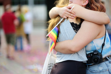 Podgorica, Montenegro - October 8, 2022: View of embracing lesbian couple with rainbow flag during...