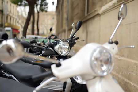 Motorcycle, scooters are parked on the city road. In old European cities there is a problem of...