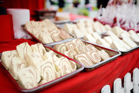 Delicious marble halvah and candy apples on outdoor Easter Europe holiday market. Homemade halva, cookies and cookies selling on traditional urban weekend fair. Handmade halwa.の写真素材
