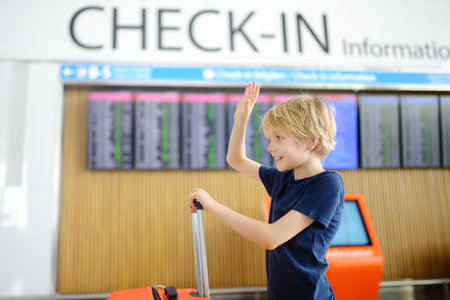 Portrait of cute preteen boy in international airport or on railway station platform near information display of timetable. Check-in. Travel, tourism, vacation, adventures for family with kidsの写真素材