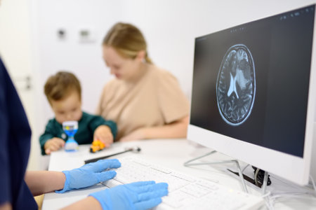 Toddler boy with his mom are at appointment with a pediatric neurologist. A doctor exploring of baby x-ray scan image brain. A practitioner provides highly qualified care in a modern medical clinicの写真素材