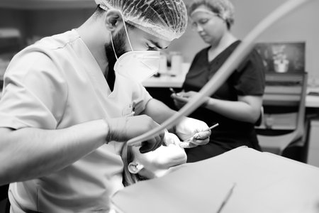 Dentist and patient at modern medical center. Doctor treats a young woman teeth in hospital. Practitioner examines the patient before orthodontists or prosthetics treatment. Black and white photoの写真素材