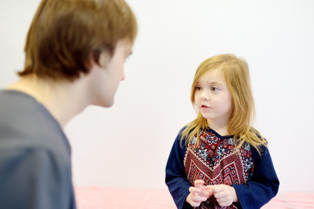 A cute girl is at an appointment with a caring pediatrician. The doctor establishes contact and trust with little patient. Viral and bacterial diseases of childrenの写真素材
