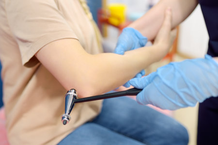 A woman at an appointment with a neurologist. A doctor examining elbow reflex of young female patient. Neurology professional doctor at workの写真素材