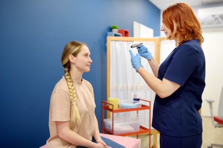 A woman at an appointment with a neurologist. A doctor examining young female patient using neurological hammer to test reflexes. Neurology professional doctor at workの写真素材