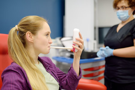 A nurse in the laboratory offers the patient a medical machine for blowing to perform a test for...