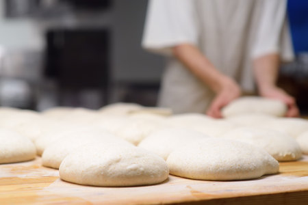 A batch of formed dough pieces on a table in the kitchen of a local bakery ready to bake. Olive...