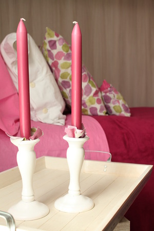 Pink candles with a bed in the backgroundの写真素材