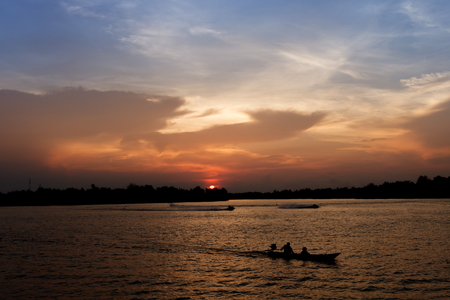 Silhouette of long tail boat on Tapee river Suratthani Thailand in evening timeの写真素材