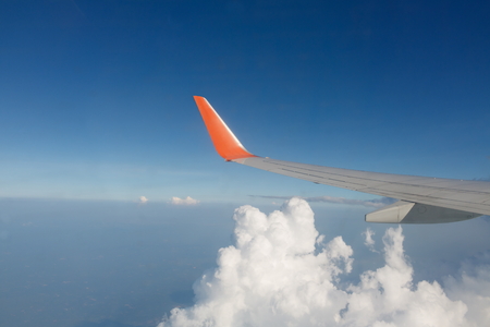 Wing of airplane flying on the white cloud, view at airplane window
