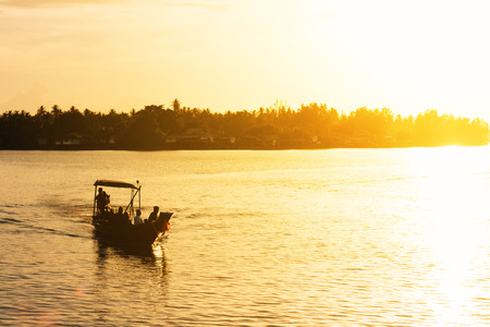 Longtail boat on river with golden evening lightの写真素材