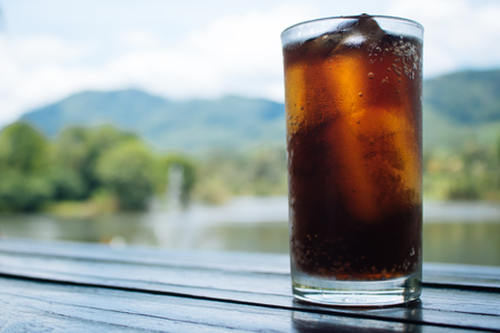 Cola in glass on table with mountain and river backgroundの写真素材