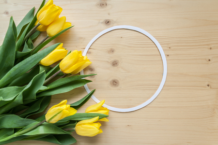 round frame and bright yellow tulips on wood backgroundの写真素材